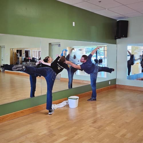 Lucas and Stacey striking dance poses while cleaning studio mirrors