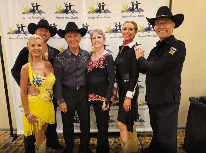Lucas and Stacey posing with students in front of an Arizona Dance Classic backdrop
