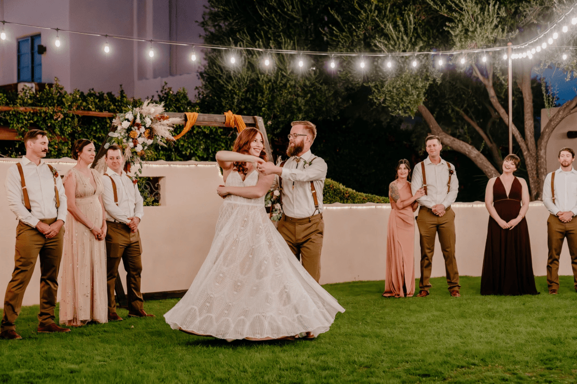 A wedding couple dancing together under hanging white lights